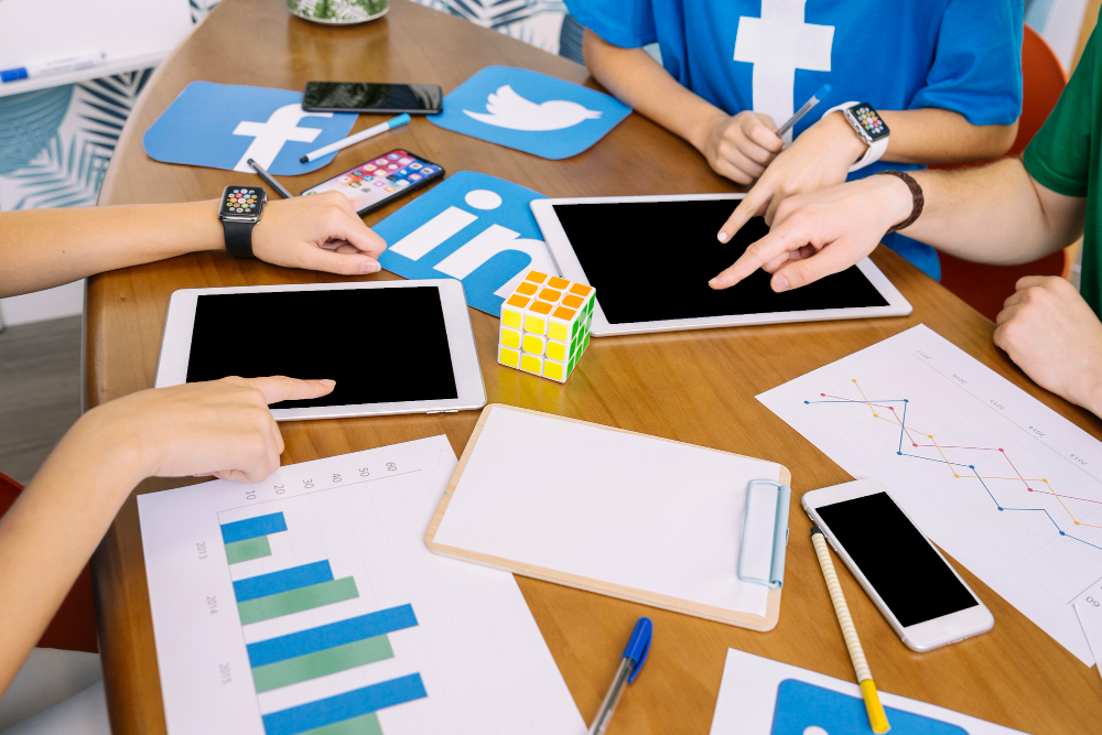 hands on a tablet with social media symbols on desk